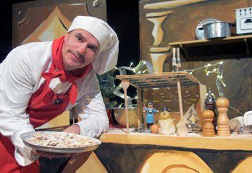 Tom Teuer steht in Kochuniform mit einem Teller Plätzchen in der Weihnachtsbäckerei