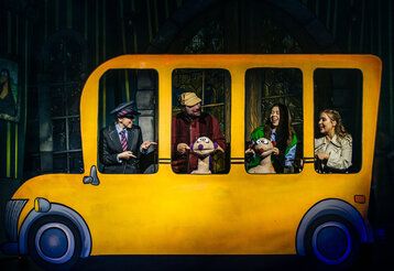 Die Puppen Jan & Henry mit Schauspielern in einem gelben Bus auf der Bühne