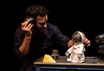 Szene aus dem Puppentheater „Armstrong“ mit der Maus Armstrong in einem Raumanzug im Gespräch mit dem Schauspieler Leo Mosler 