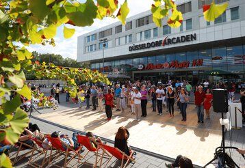 Menschengruppe tanzt in Formation vor einem Einkaufszentrum