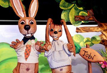 Zwei Hasenpuppen mit weißen Pullovern auf der Bühne des Puppentheaters Helmholtzstrasse.