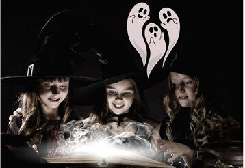 Drei als Hexen verkleidete Mädchen stehen an einem dampfenden Hexenkessel.