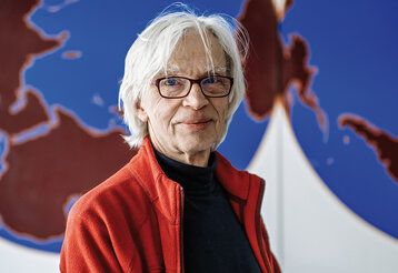 Günther Haverkamp sitzt vor einer Weltkarte