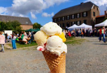 Eine große Eiswaffel wird ins Bild gehalten mit einem Fest im Hintergund 