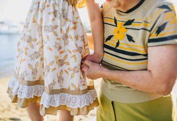 Eine Großmutter und ihre Enkelin halten am Strand ihre Hände.