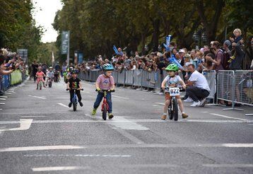 Kleine Kinder fahren auf ihren Laufrädern beim Radrennen „Rund um die Kö“ um die Wette