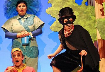Schauspieler der Burghofbühne Dinslaken spielen vor einer Kulisse von Bäumen und blauem Himmel.