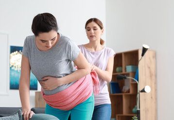 Doula massaging pregnant woman at home