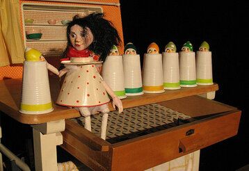 Bühnenbild von „Schneewittchen“, gespielt vom Theater Fadenschein, mit der Schneewittchen Puppe auf einem Küchenregal sitzend.