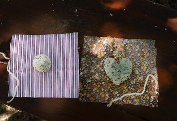 Zwei selbstgemachte Seifen liegen auf bunten Stoffquadraten 