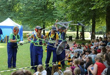 Schauspieler spielen im Park vor einer Gruppe Kinder