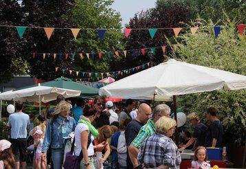 Besucher des Straßenfests in der Tannenhofsiedlung Vennhausen spazieren an bunt geschmückten Ständen vorbei.