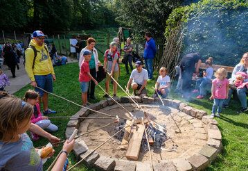 Kinder grillen Würstchen über einer Feuerstelle im Rahmen des Wildparkfests.