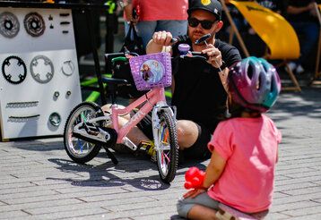 Mann prüft Kinderfahrrad, Kind guckt zu