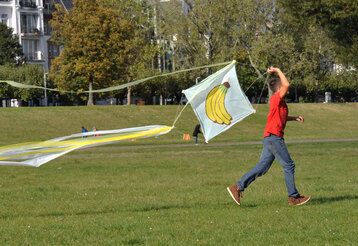 Kind läuft mit einem Drachen auf der Rheinwiese