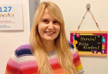 Porträt von Alina Votruba mit gestreiftem Pullover vor Zimmertür