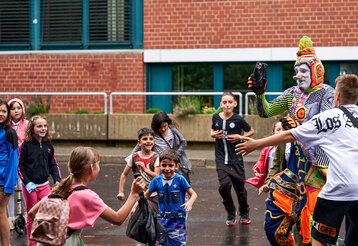 verkleideter Künstler spielt mit Kindern beim Artistik Festival