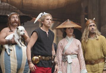 Asterix und Oberlix stehen zusammen mit einer Chinesin und einem Wikinger, Obelix trägt Hund Idefix auf dem Arm, alle gucken überrascht