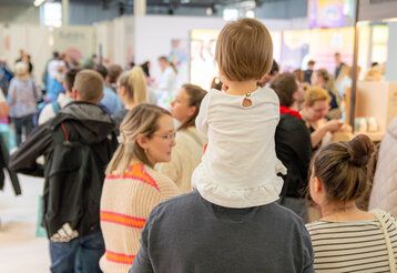 Besucher von hinten bei Babini Messe, Mann trägt Kind auf den Schultern