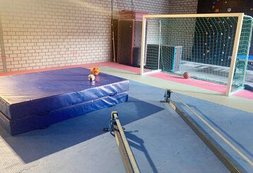 Turnhalle von innen, dicke Matte, Fußballtor, Bälle, keine Menschen