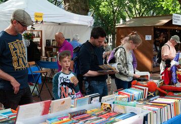 Besucher des Bücherbummels auf der Düsseldorfer Kö zwischen Bücherständen, einige blättern in Büchern