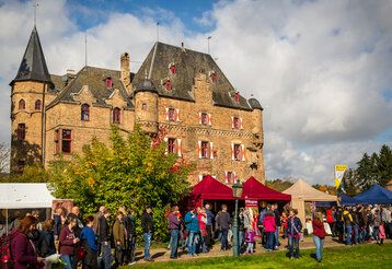 Marktstände und Besucher:innen vor Burg Satzvey