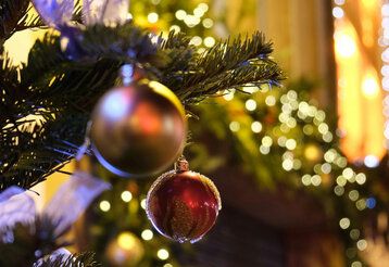 Christbaumkugeln am Baum, im Hintergrund verschwommene Lichter