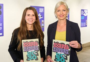 Clara Gerlach und Stephanie Widholm präsentieren Flyer der Düsseldorfer Kinderagenda 2030
