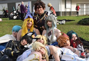 Cosplayer sitzen zusammen auf einer Rasenfläche bei einer Veranstaltung