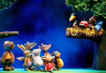 Verschiendene Waldtiere stehen vor einem Baum und starren hinauf auf einen Ast, auf dem Rabe Socke sitzt.