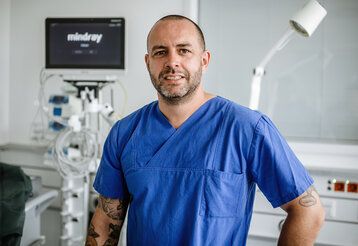 Mann in blauer Pflegerbekleidung in Untersuchungszimmer