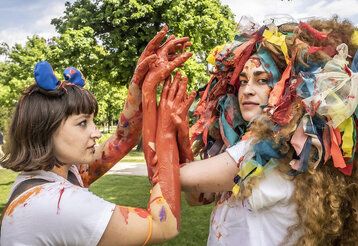 zwei Schauspielerinen, bunt als Löwen verkleidet spielen im Park
