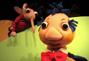 Zwei Puppefiguren, ein Käfer und ein Mann auf Puppenbühne