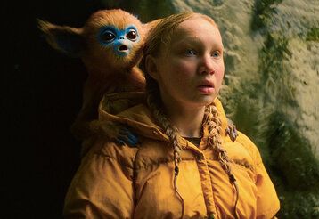 ein Mädchen steht vor einer Felswand und guckt erstaunt, hinter ihr ist ein Ochi und guckt genauso erstaunt