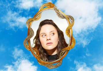 Das Bild einer jungen Frau in einem Spiegel vor blauem Himmel mit Wolken, Die unendliche Geschichte Junges Schauspiel