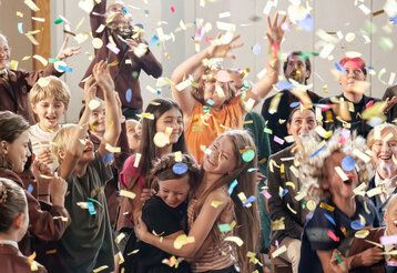 Gruppe von Schülern und Schülerinnen im Konfettiregen