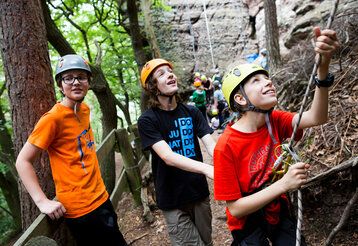 Drei Jugendliche mit Kletterausrüstung in Nideggen im Wald