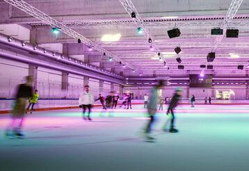 Innenraum der Eissporthalle Benrath, Schlittschuhläufer:innen mit Bewegungsunschärfe