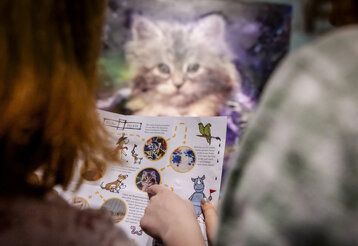 Personen gucken ins Entdeckerheft zu Monet, Cezanne, Matisse vom Kunstpalast, im Hintergrund ein Katzenbild