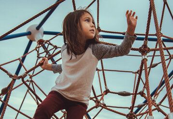 Mädchen klettert auf einem Seil-Klettergerüst herum