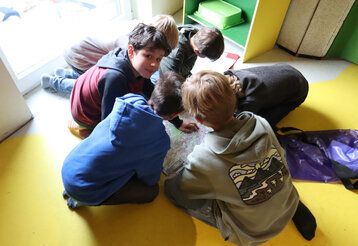 Sechs Jungs sitzen auf dem Boden und gucken sich eine Landkarte an