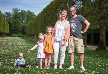 Vater, Mutter und zwei Kinder stehen wie die Orgelpfeifen im Benrather Schlosspark, ein Baby sitzt daneben im Gras