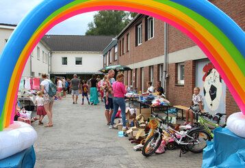 Trödelstände in Wohnsiedlung, im Vordergrund ein aufblasbarer Regenbogen
