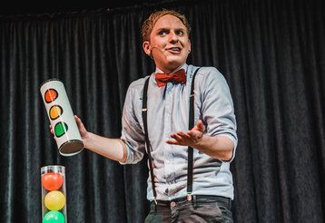 Zauberer Felix Wohlfahrt auf der Bühne, vor grauem Vorhang