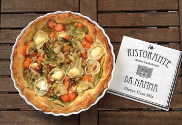 Fenchel-Karotten-Tarte von oben fotografiert mit einer Serviette, auf der steht: Ristorante da Mama, auf Holztisch
