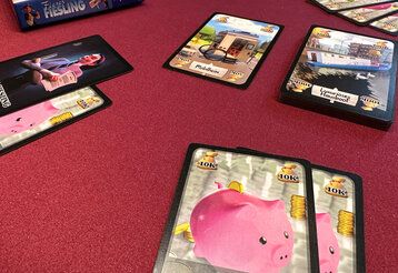 Spielkarten des Spiels Fieser Fiesling liegen auf rotem Untergrund