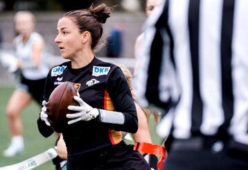 Flag Football Spielerin beim Spiel, im Vordergrund ein Schiedsrichter von hinten im gestreiften Shirt