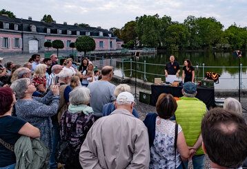 Guido Hoehne und Judith Funk sprechen vor dem Benrather Schloss über Fledermäuse, eine Gruppe von Leuten hört zu