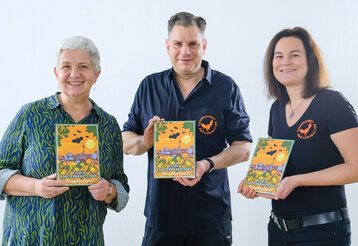 Guido Hoehne, Judith Funk und Doris Törkel präsentieren die Blumensamenmischung „Fledis Flatterkraftstoff“