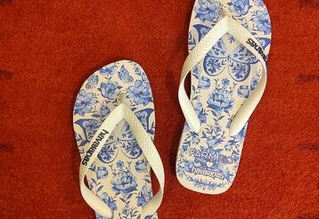 Flip-Flops mit blauem Blumenmuster auf rotem Teppich